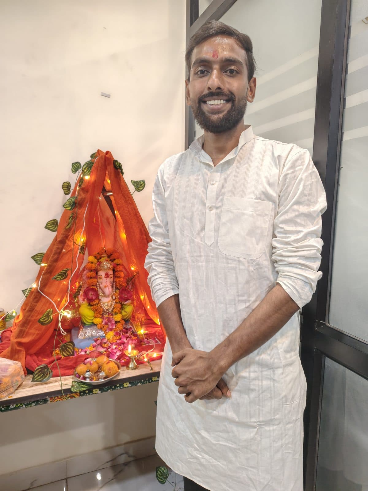 TradeAura mentor in a white kurta standing beside the decorated Ganpati mandap