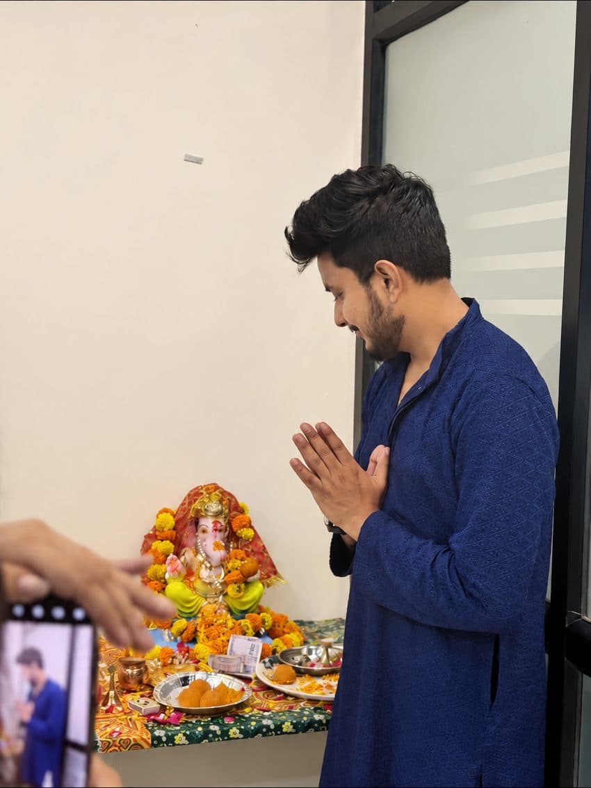 TradeAura team member praying with folded hands before the Ganesh idol