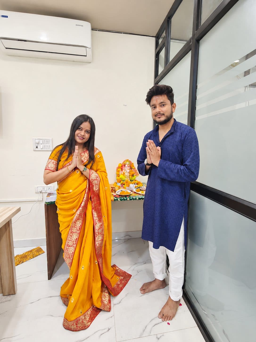Two TradeAura team members greeting with folded hands near the Ganesh idol