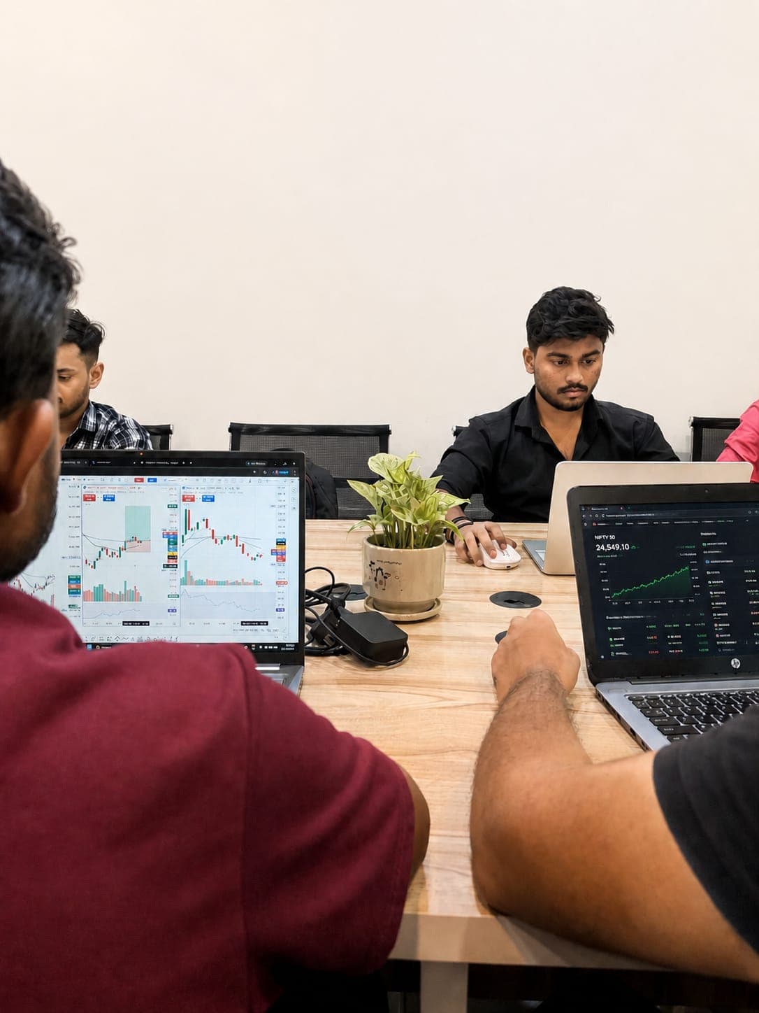 TradeAura students analysing live NIFTY 50 and TradingView candlestick charts on laptops during a trading session