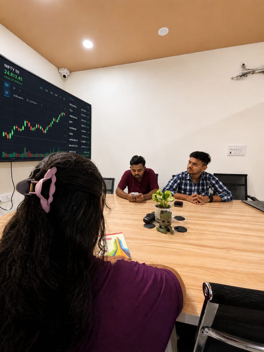 Student reviewing the live NIFTY 50 index on a large wall screen with a mentor at TradeAura Institute